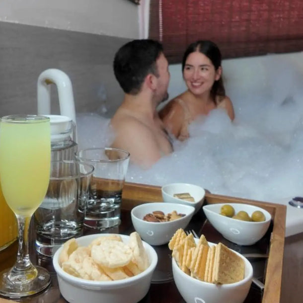 Pareja disfrutando de un baño de hidromasaje con bebidas y aperitivos