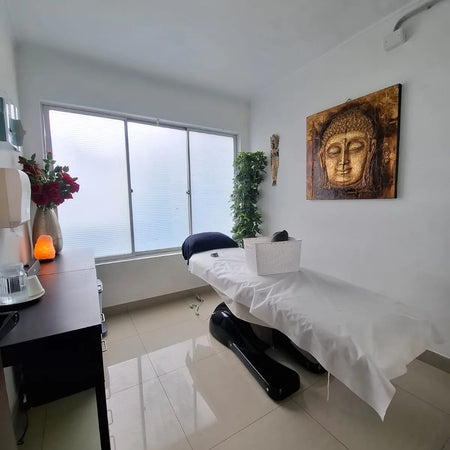 Sala de tratamientos spa con camilla, luz cálida y decoración de Buda